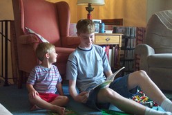 Phil and Will seated on the floor, with a book