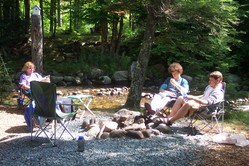 Kathy, Kevin, and Steve seated around the fire ring, with the river in the background