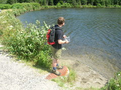 Steve standing at the edge of a lake, with trees along the far shore