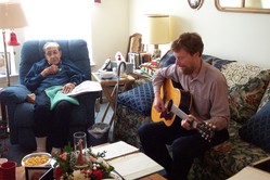 Rico in his chair, with Scott nearby playing the guitar