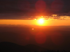 the yellow sun between clouds above and mountains below